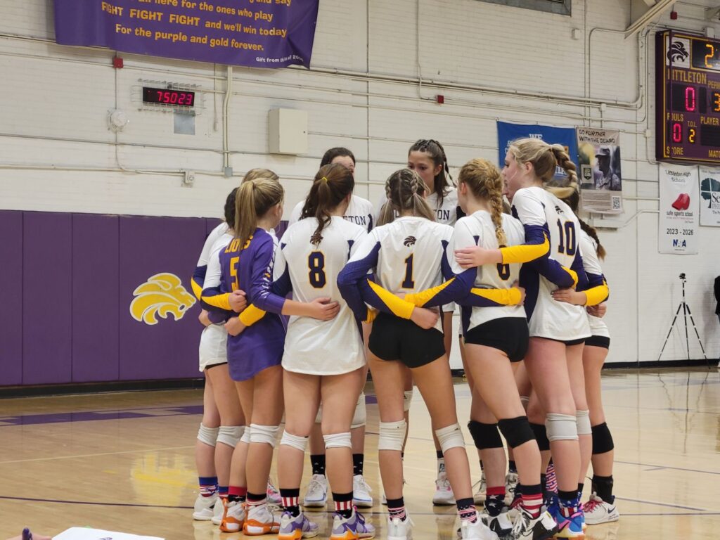 Girls' volleyball team gathered in a team huddle