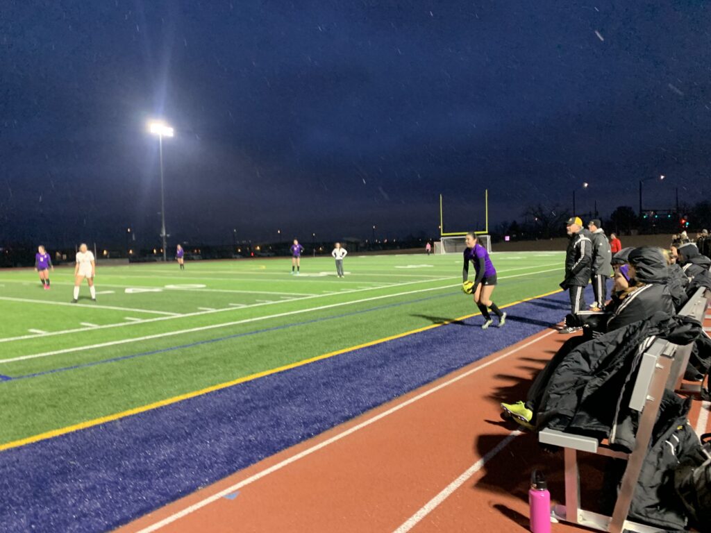 LHS throws ball back onto pitch at first girls soccer game.