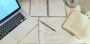 A desk littered with books and an open laptop