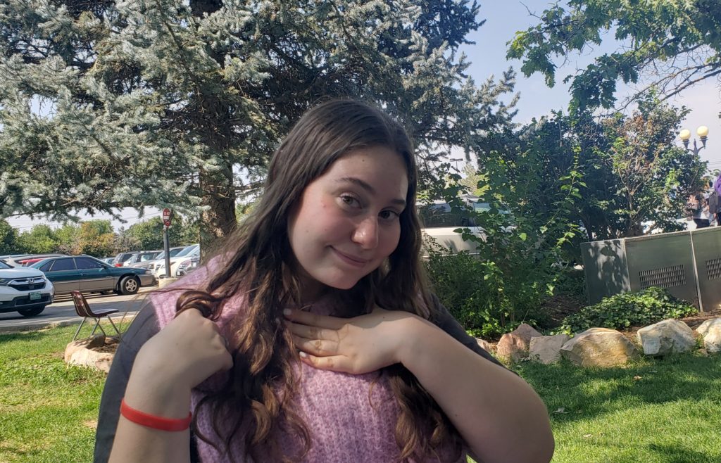 A girl smiles with a hand posed under her chin