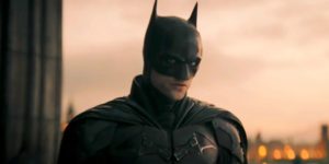 Batman stands against a sunset