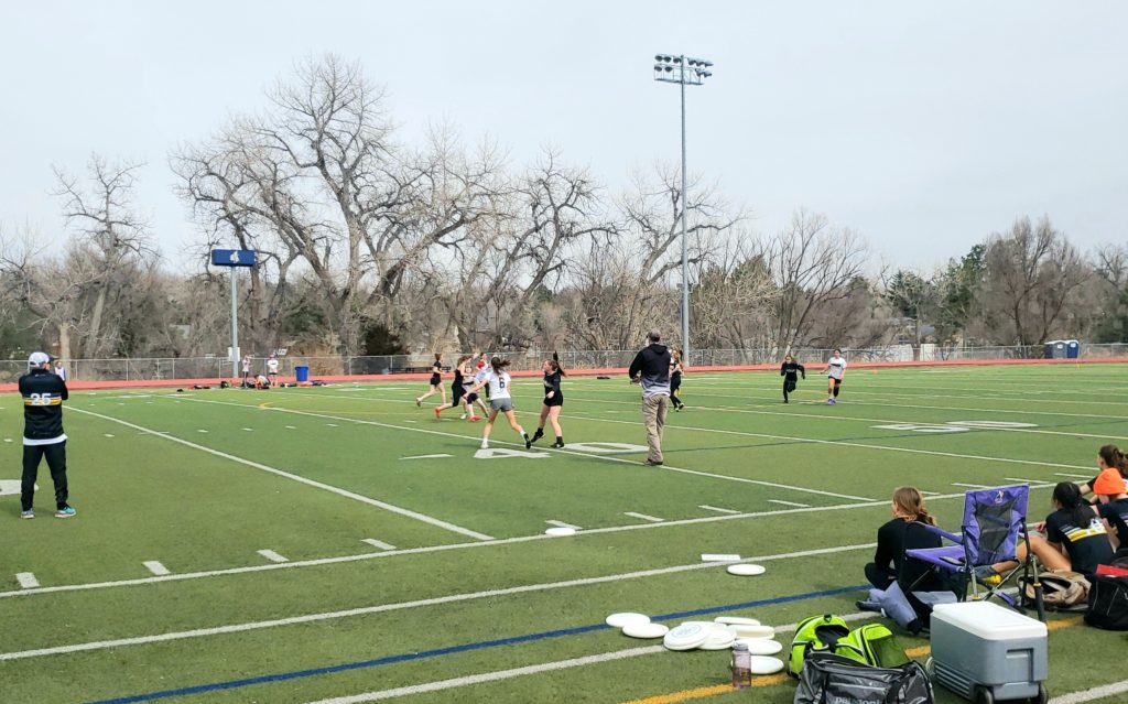 Girls play ultimate frisbee on the district football field